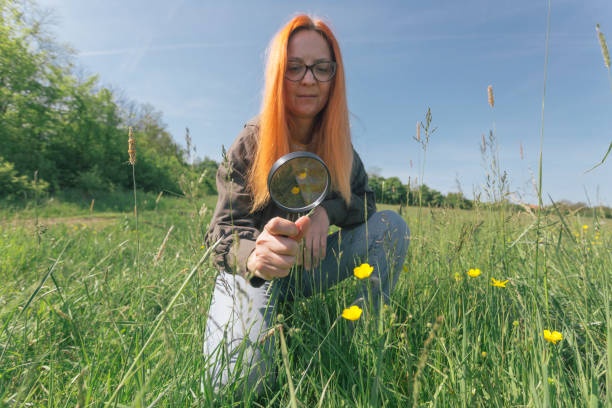 woman looking at a plant with a magnifying glass