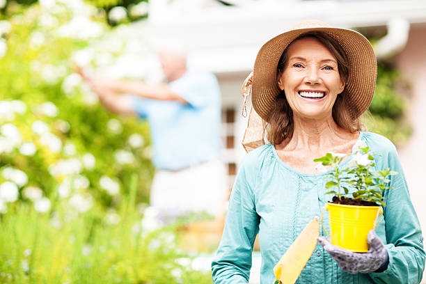 person holding a small potted plant, smiling, bright sunlight