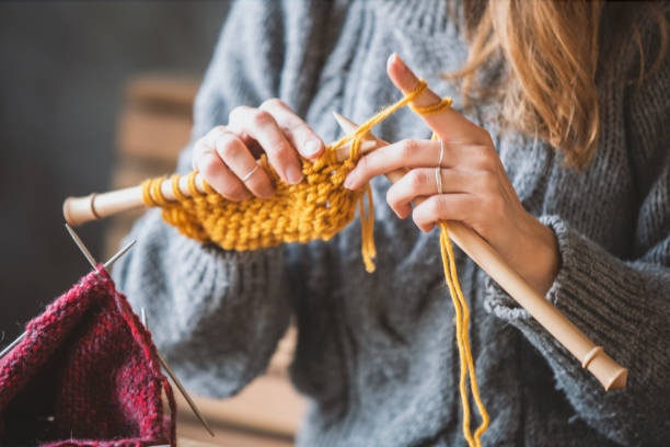 close up of hands knitting, warm lighting, cozy atmosphere