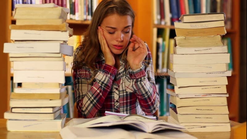 person looking stressed, surrounded by books and notes