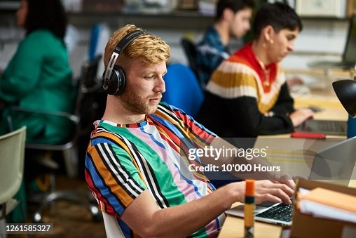 person working on laptop with noise-canceling headphones