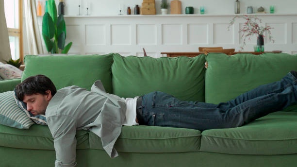 person looking tired, sitting on couch, low light