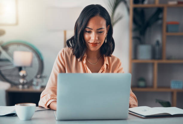 person smiling, working on laptop, bright room