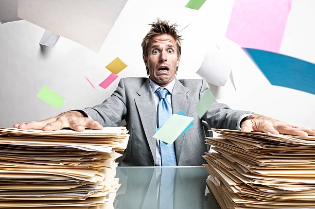 director looking frustrated, surrounded by paperwork