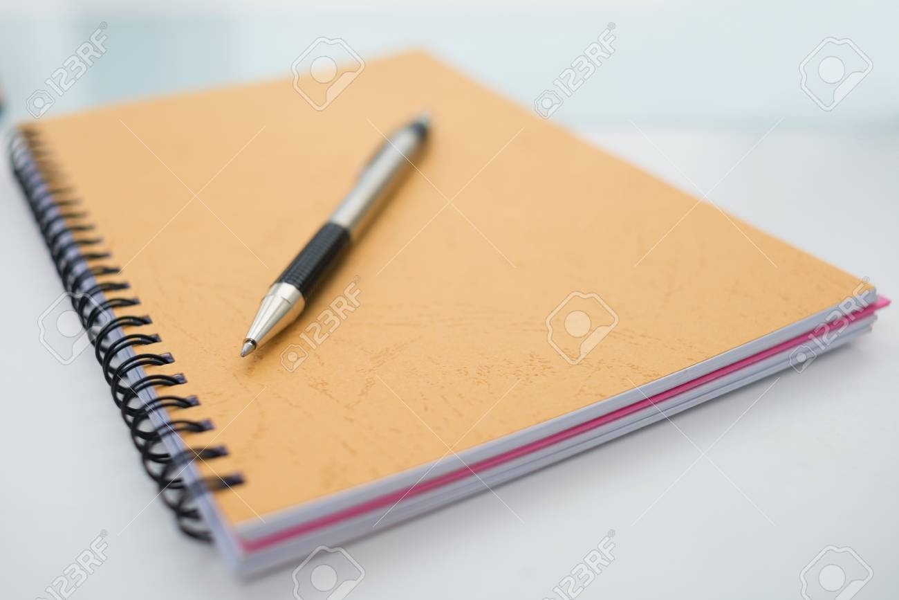 notepad and pen lying on a desk