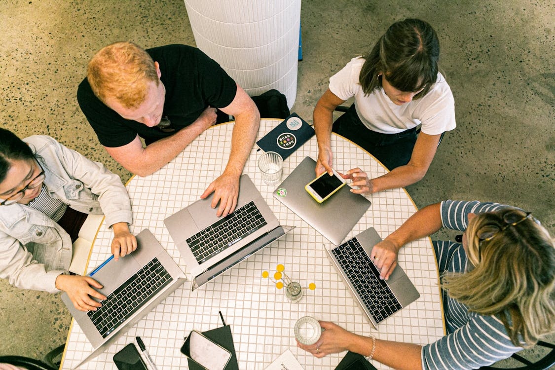 group of people using laptops and phones, working remotely