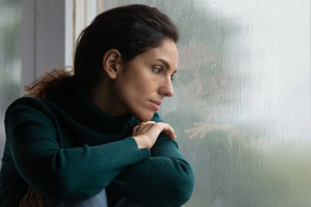 person looking out window, thoughtful, rainy day