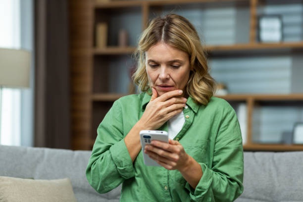 person reading horoscope app on phone, worried expression