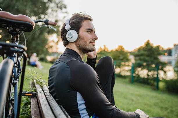 person wearing open-ear headphones while cycling, sunny day