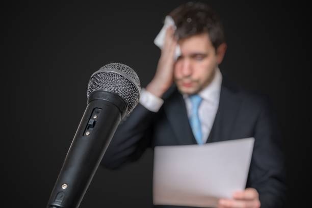 person looking nervous while speaking, microphone, stage